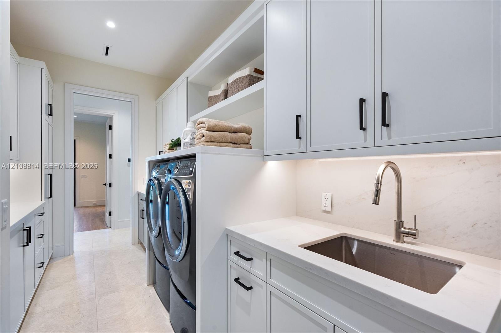 Laundry area featuring Shaker-style cabinetry, quartz countertops, a stainless steel undermount sink with a gooseneck faucet, light-toned stone-finish