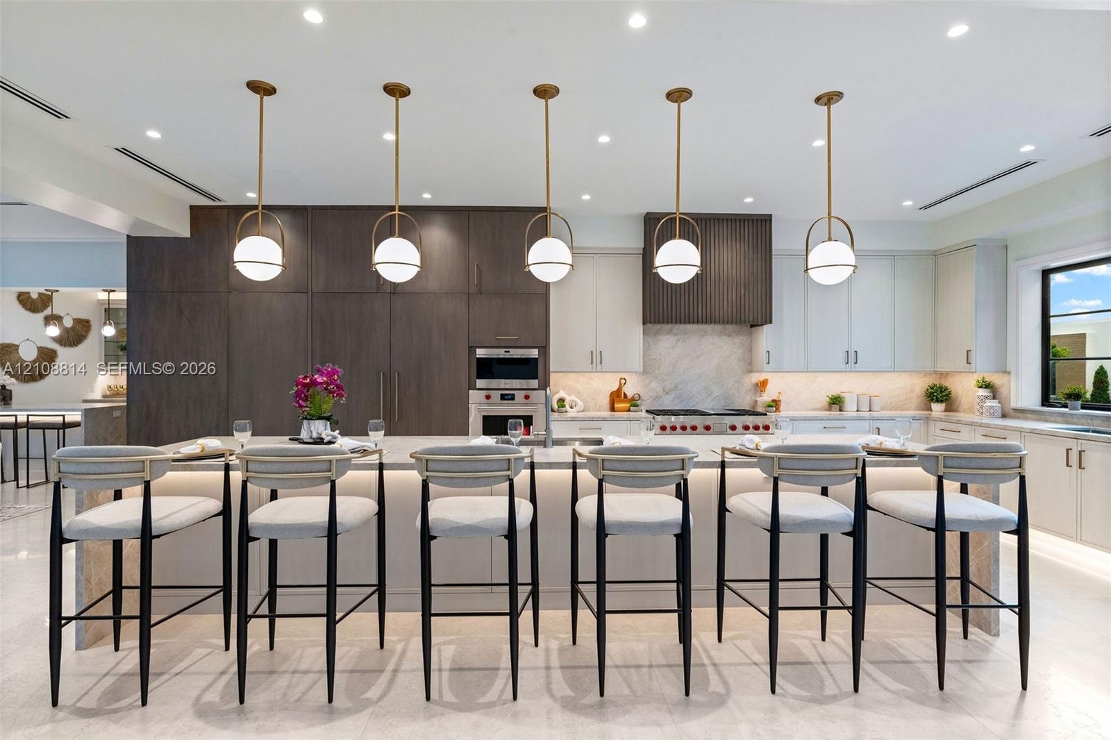 Kitchen featuring a large central island with waterfall-edge stone countertop, custom cabinetry, integrated professional-grade appliances, recessed li