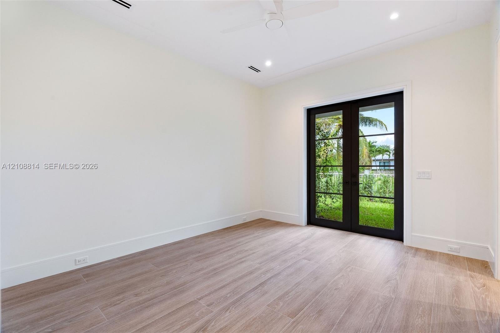 Neutral interior featuring porcelain-finish flooring, recessed lighting, a ceiling fan, and French doors with black frames opening to exterior landsca