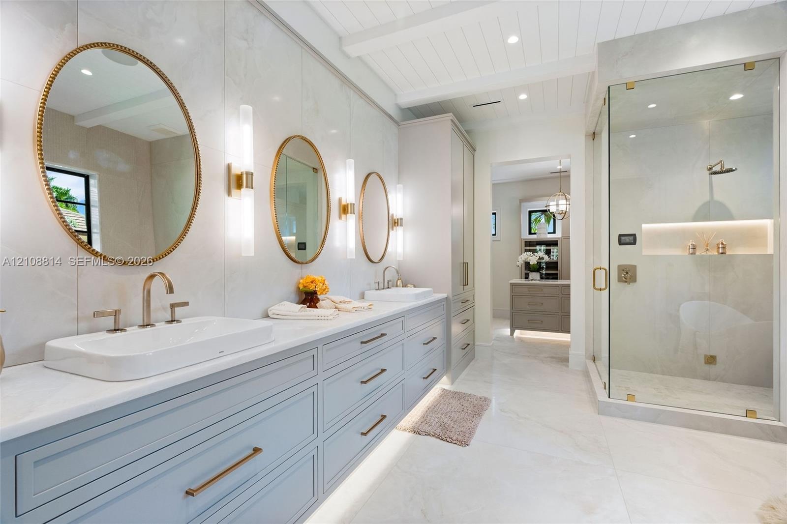 Dual-basin vanity featuring quartz countertops, large-format tile wall cladding, glass-enclosed walk-in shower with integrated recessed shelving, and 