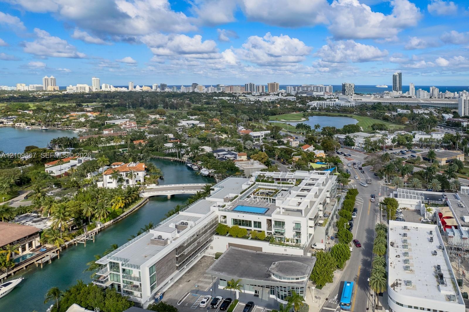 Aerial perspective of a multi-story residential complex featuring a rooftop swimming pool, private balconies, and landscaped courtyard, situated on a 