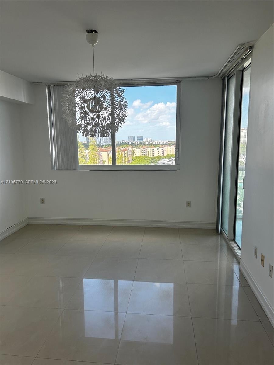 Large-format tile flooring, oversized window, built-in decorative pendant light, and glass sliding door