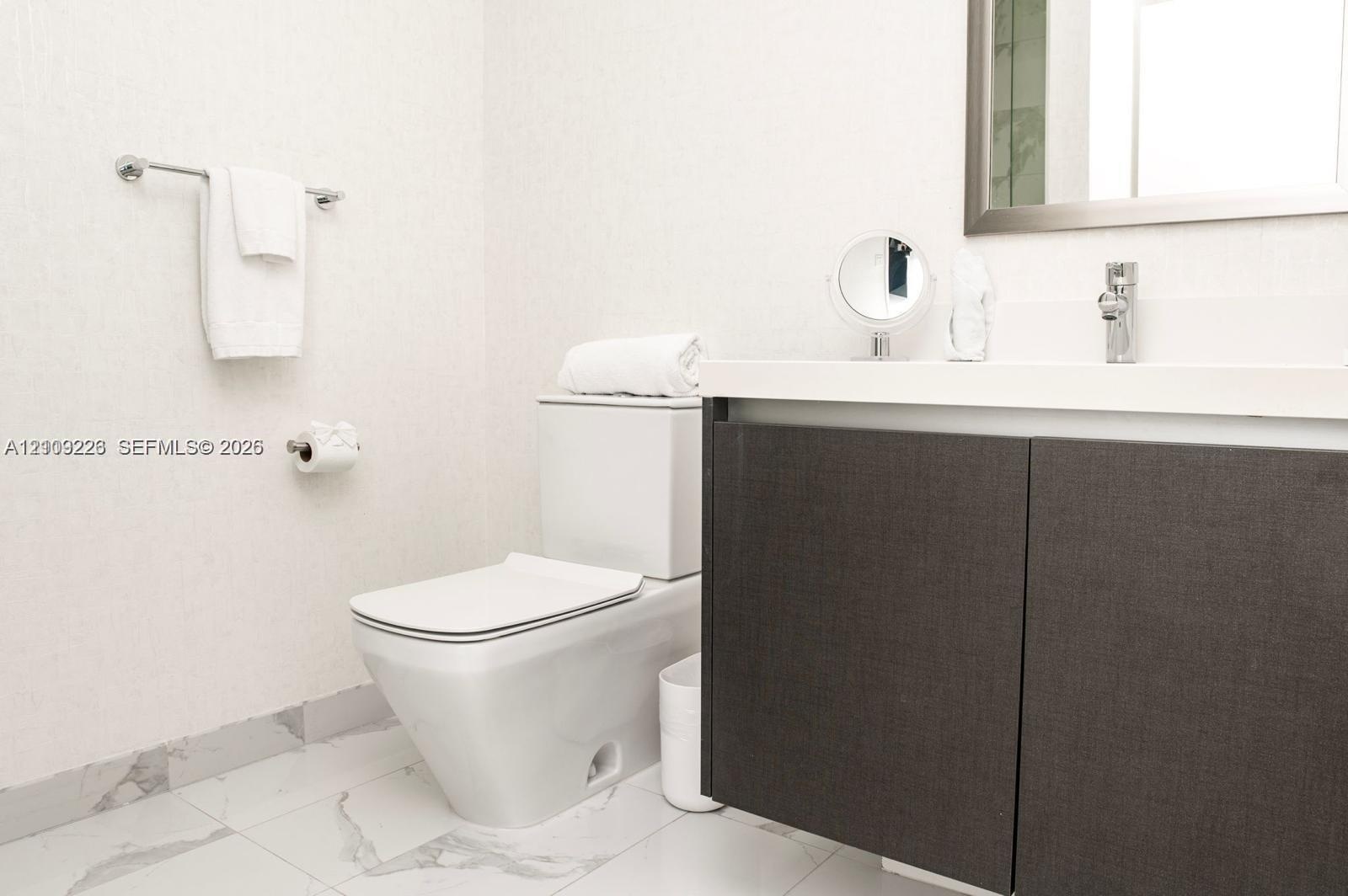 Modern floating vanity with a solid-surface countertop and integrated sink, complemented by a dual-tone charcoal cabinet, chrome-finished wall-mounted