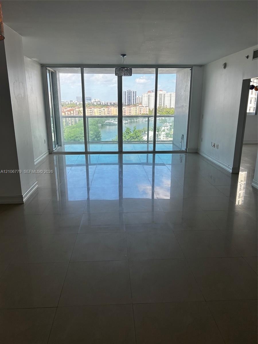 Floor-to-ceiling glass windows, polished tile flooring, glass balcony railing, and natural lighting