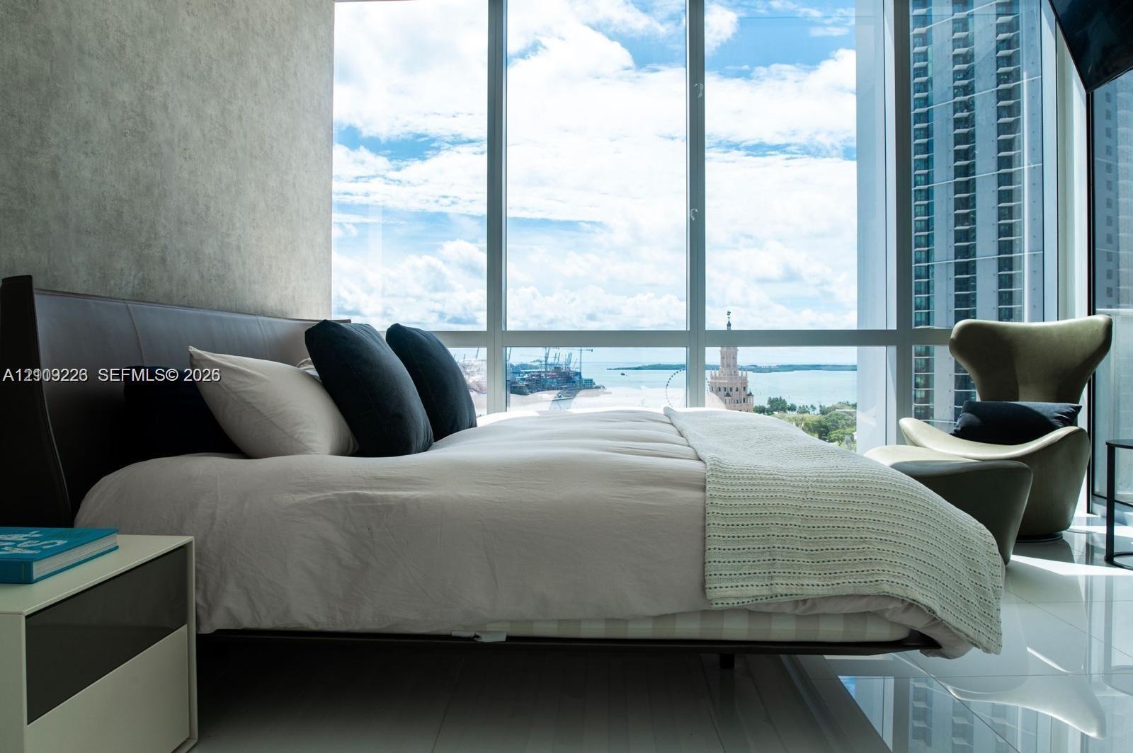 Floor-to-ceiling windows featuring panoramic maritime and urban scenery, complemented by polished tile flooring and a textured accent wall