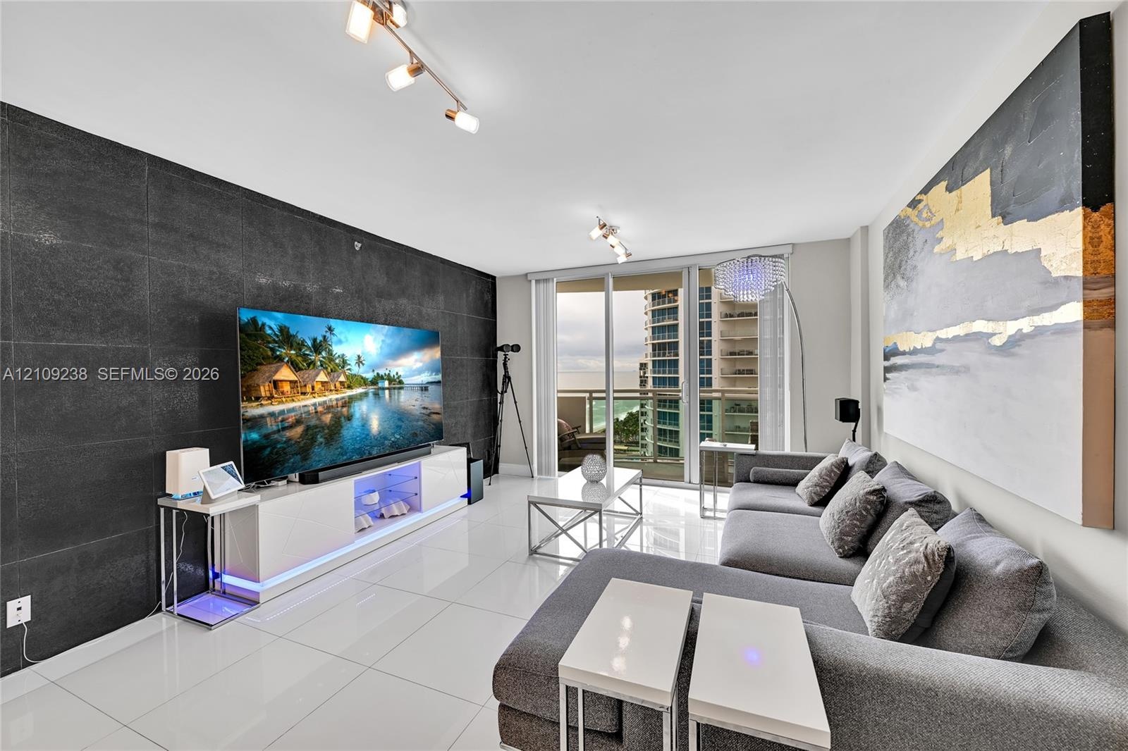 Large-format tile accent wall, polished tile flooring, and floor-to-ceiling glass door