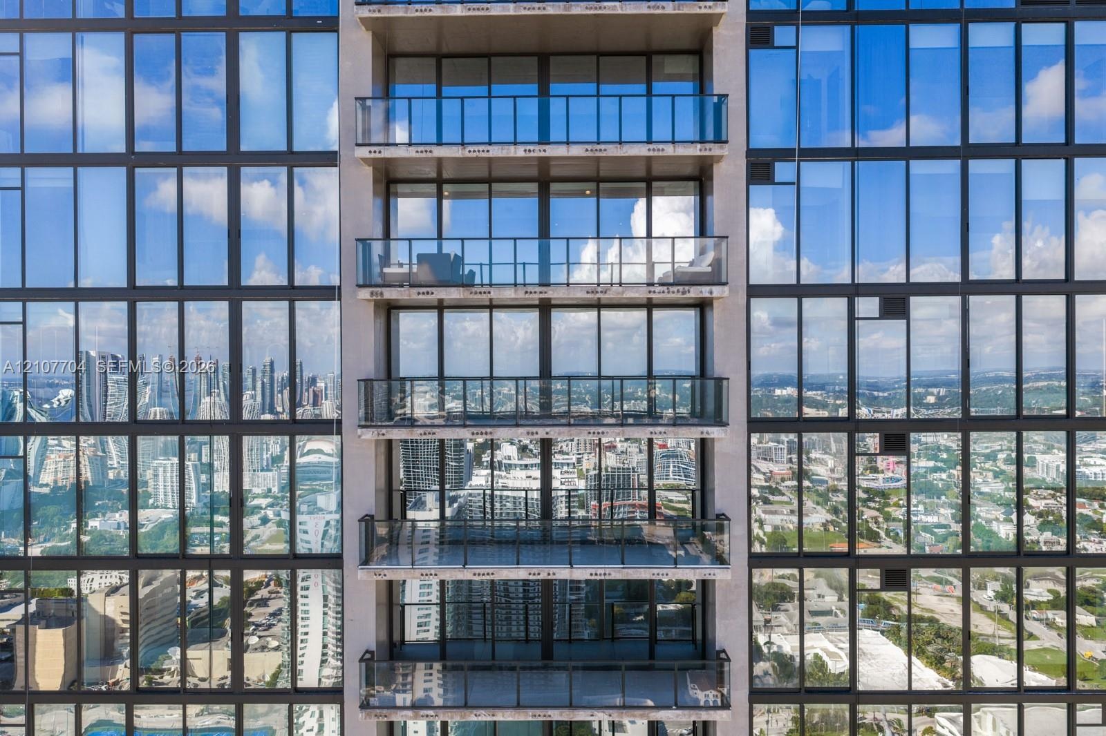 High-rise exterior featuring floor-to-ceiling glass windows and private balconies with glass railings