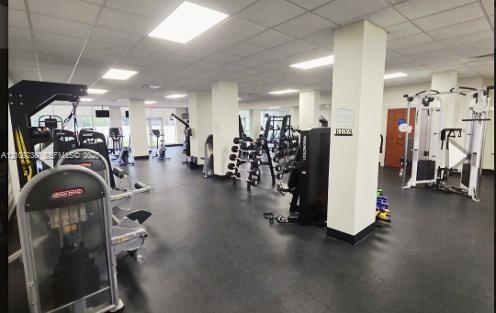 Expansive fitness center featuring recessed ceiling lighting, structural support columns, and durable rubberized flooring