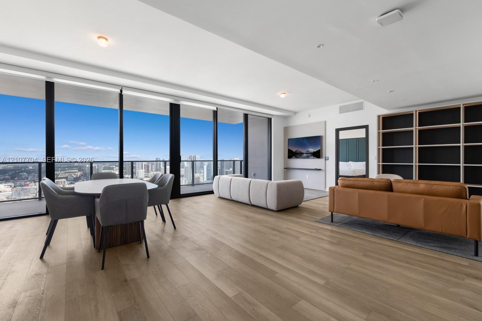 Floor-to-ceiling windows, wood-finish flooring, built-in shelving, recessed lighting, and a private balcony