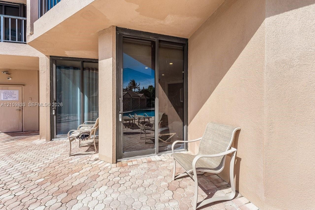 Covered patio featuring concrete paver flooring, dual sliding glass doors, and stucco exterior walls