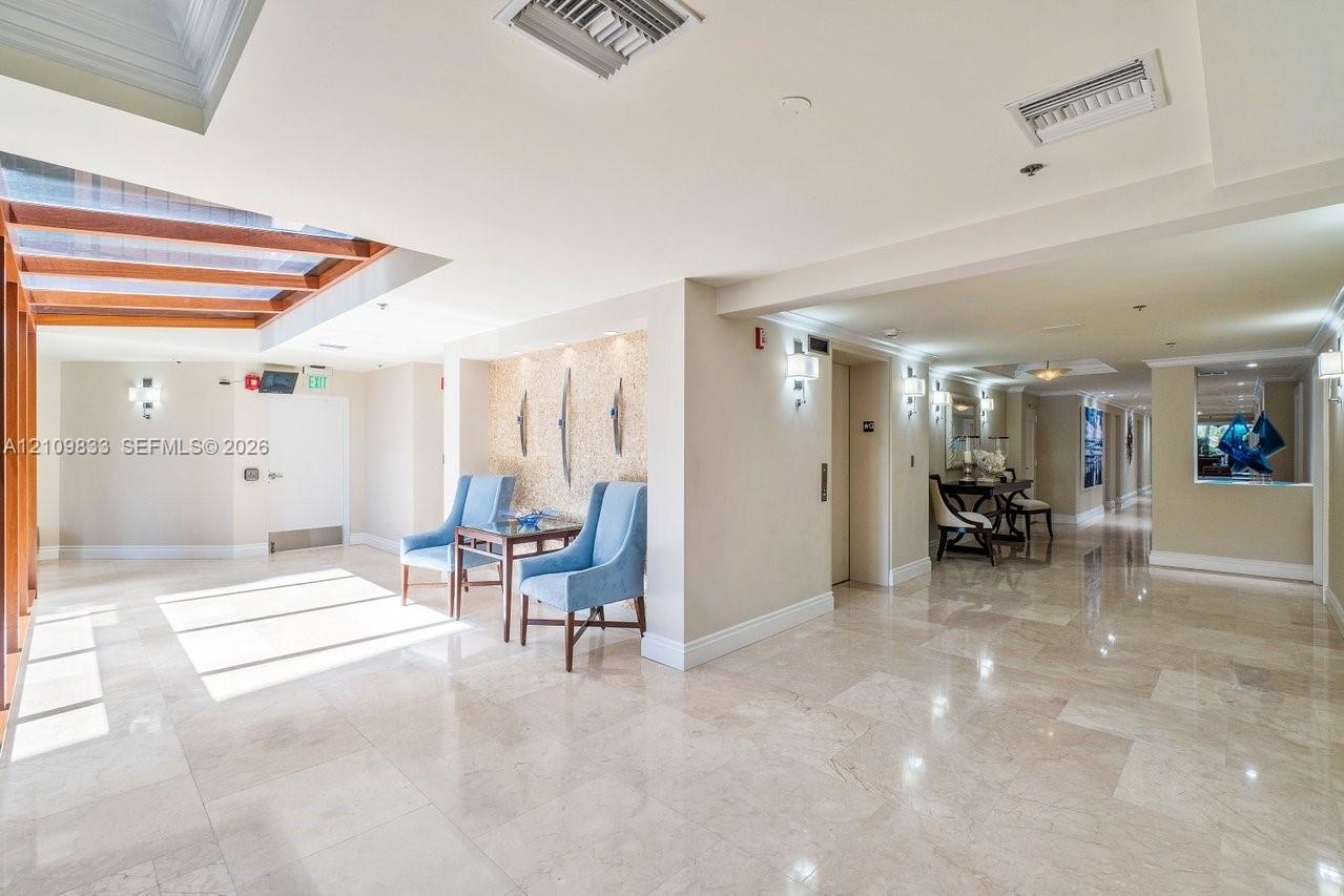 Polished stone flooring, recessed ceiling lighting, wall-mounted light fixtures, and a decorative recessed niche with textured detailing