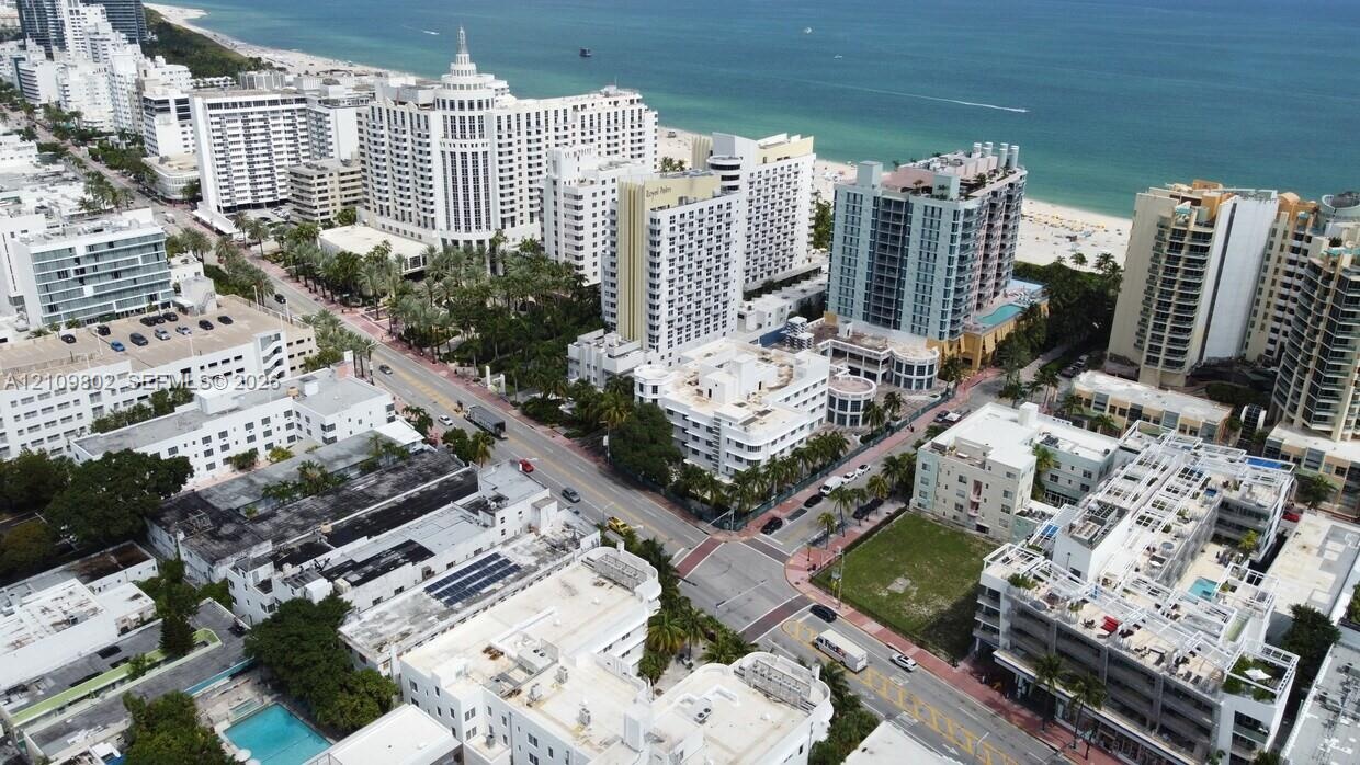 Aerial perspective of urban coastal surroundings featuring multi-story high-rise architecture, proximity to the coastline, paved thoroughfares, and ma