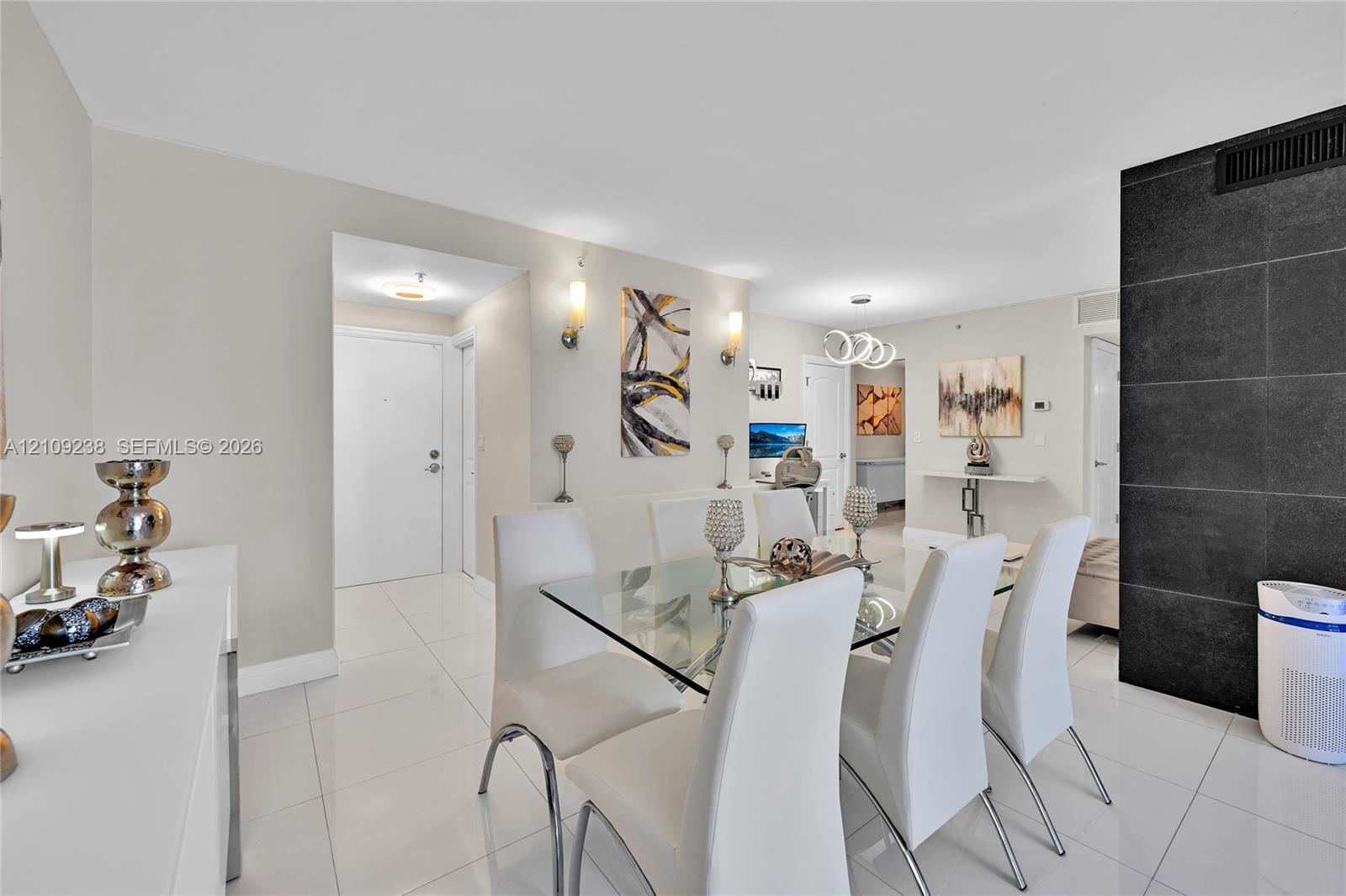 Open-concept interior featuring large-format tile flooring, a prominent black stone feature wall, dual wall-mounted light fixtures, and recessed ceili