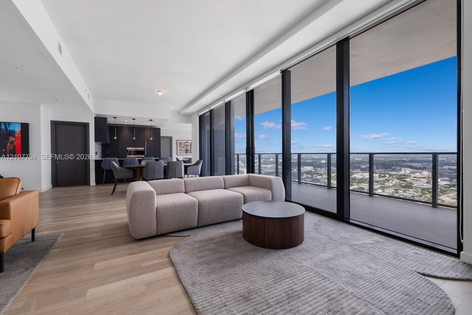 Floor-to-ceiling glass windows, expansive private balcony, wood-finish flooring, and integrated cabinetry