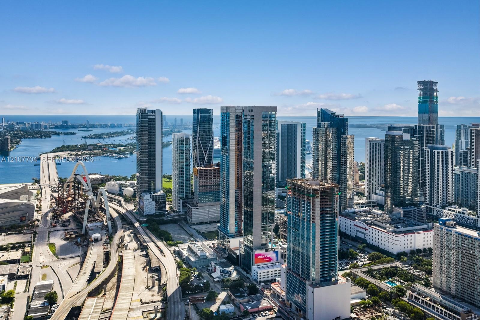 Aerial perspective of the metropolitan skyline, featuring high-rise glass-facade structures, surrounding waterway access, and urban infrastructure