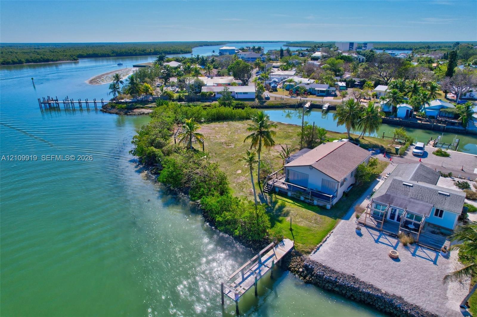 Waterfront property featuring a private boat dock, extensive shoreline, and mature palm trees