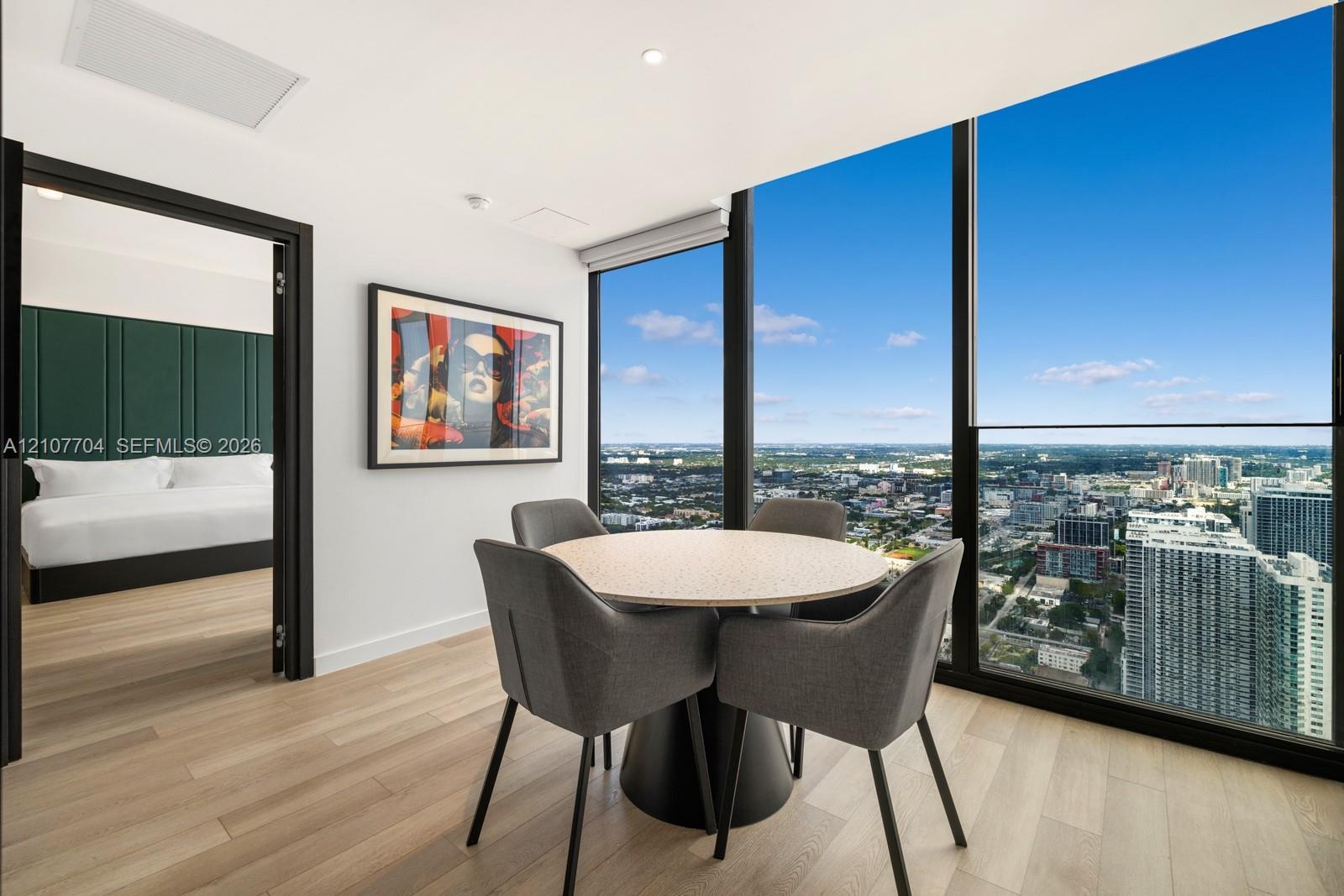Floor-to-ceiling windows, wood-finish flooring, recessed lighting, and urban skyline backdrop
