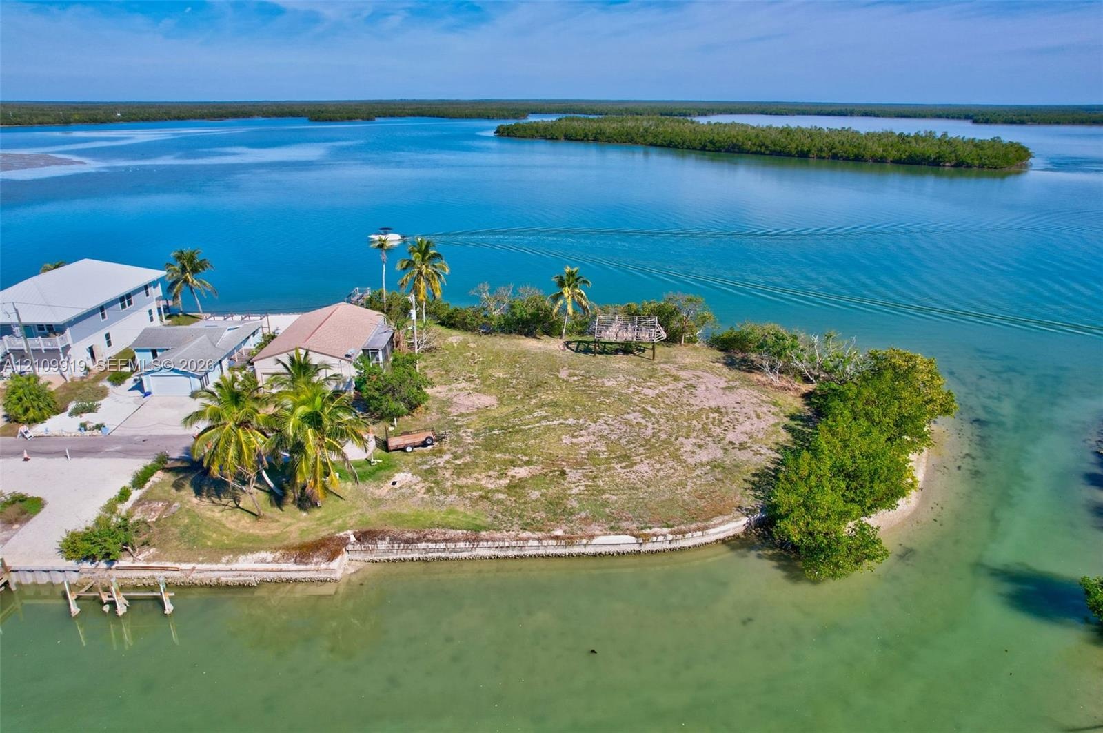 Waterfront property featuring a concrete seawall, established palm trees, and a private dock structure