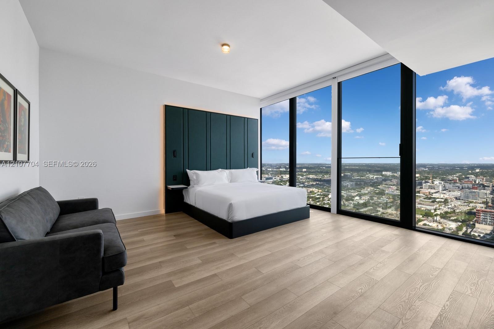 Floor-to-ceiling windows, wood-finish flooring, and built-in upholstered headboard wall paneling
