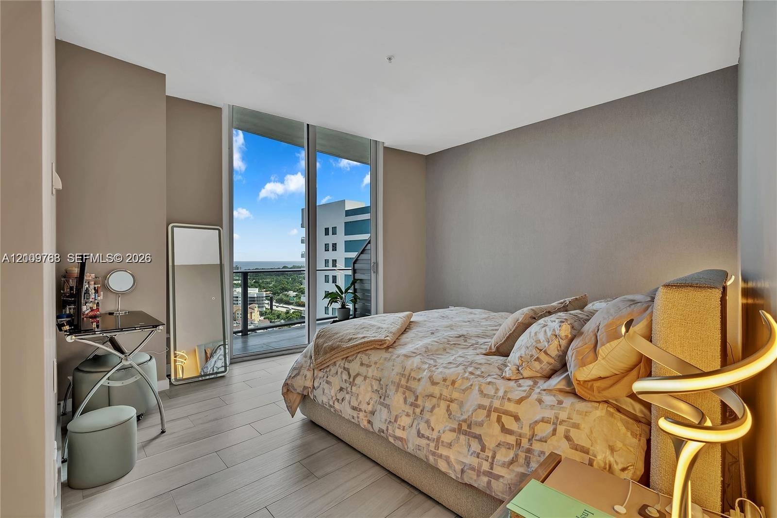 Floor-to-ceiling glass sliding doors, private balcony, and wood-finish flooring