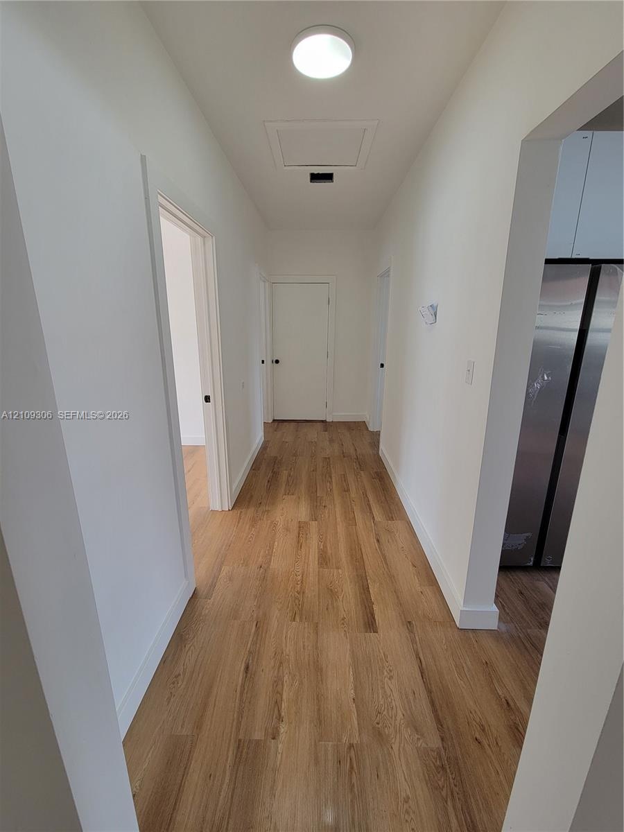 Hallway featuring wood-finish flooring, white walls, and flush-mount ceiling lighting