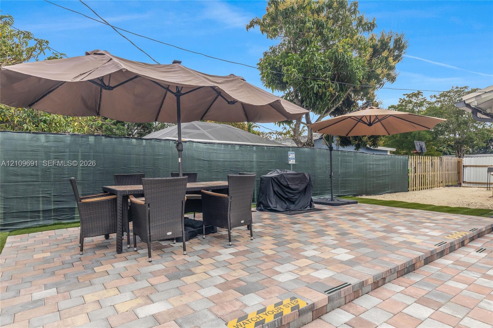 Outdoor patio featuring multi-tonal concrete pavers, tiered levels, and a privacy screen perimeter