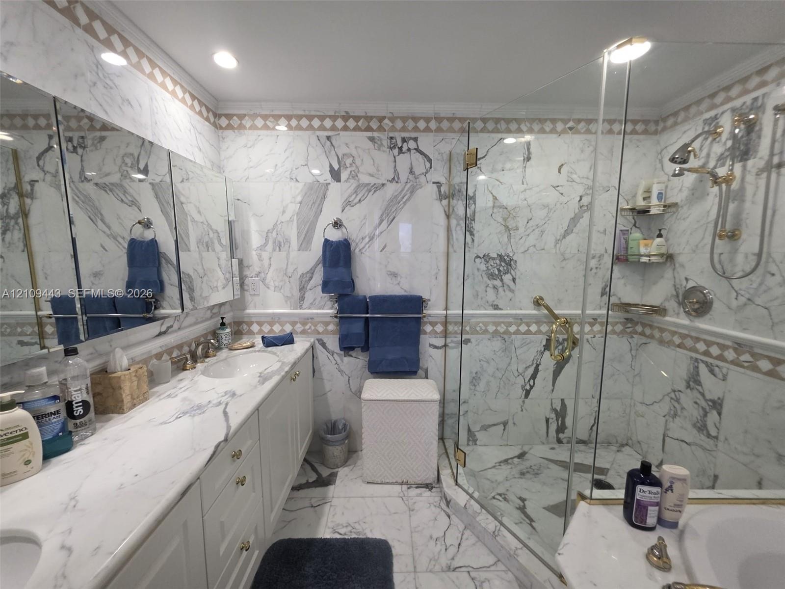 Bathroom featuring full-height stone wall tiling, a double vanity with stone countertop, recessed lighting, and a walk-in glass-enclosed shower with g