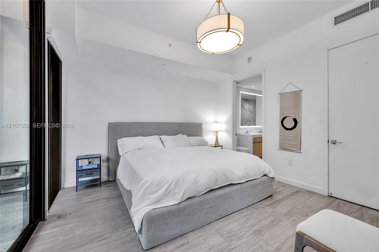 Neutral-toned wood-finish flooring, recessed ceiling lighting, contemporary drum chandelier, and solid-core interior doors