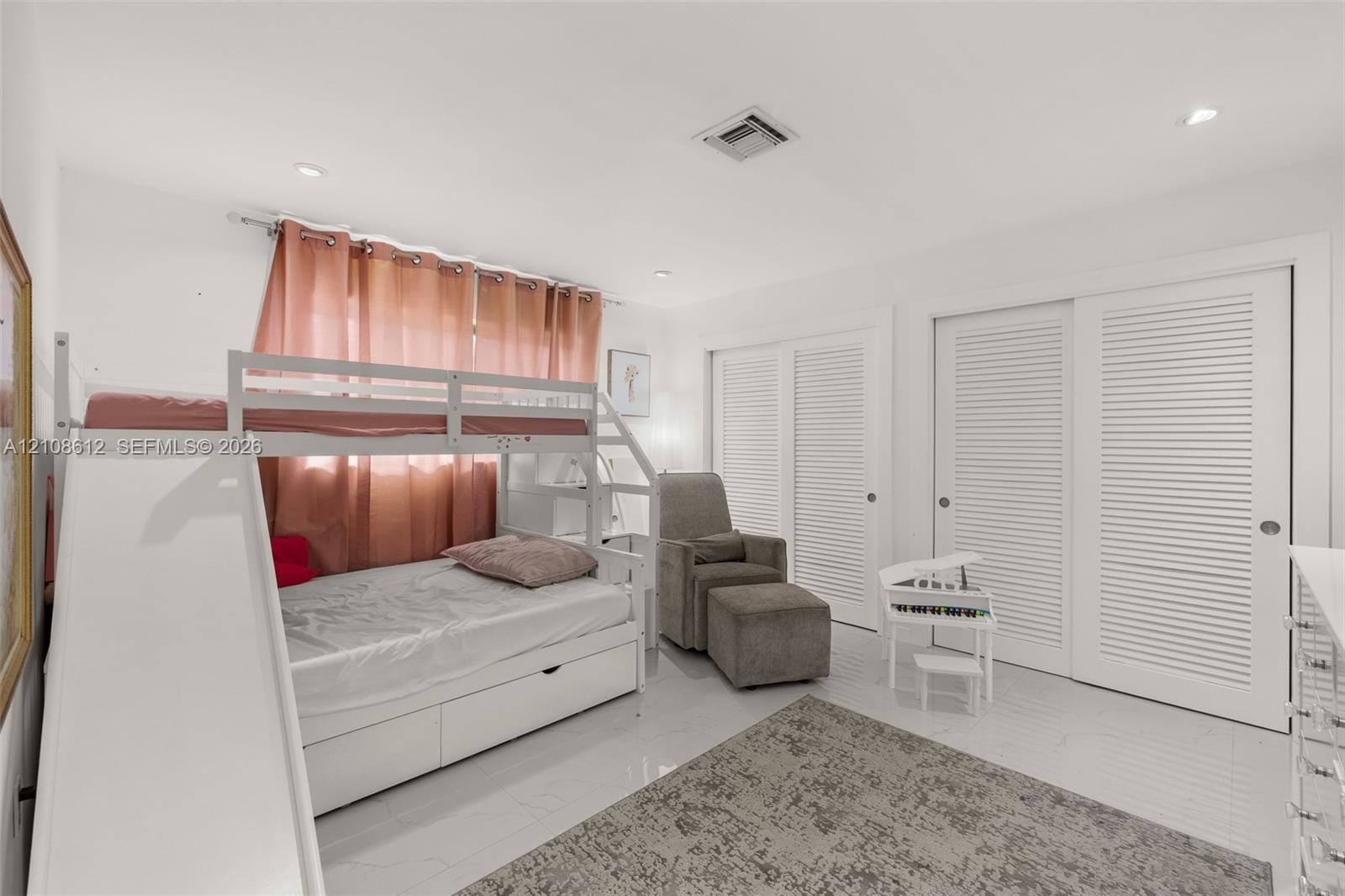 Neutral interior featuring large-format tile flooring, recessed ceiling lighting, and double closets with white louvered doors