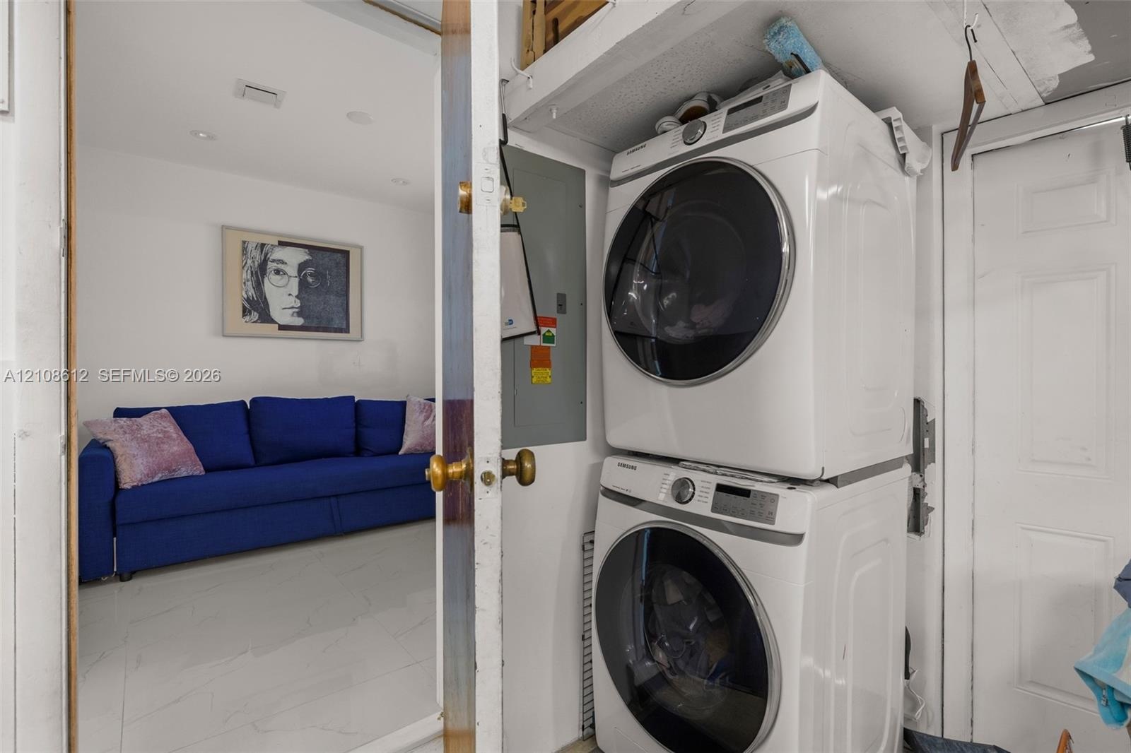 Stacked front-load laundry appliances with integrated shelving and white tile flooring