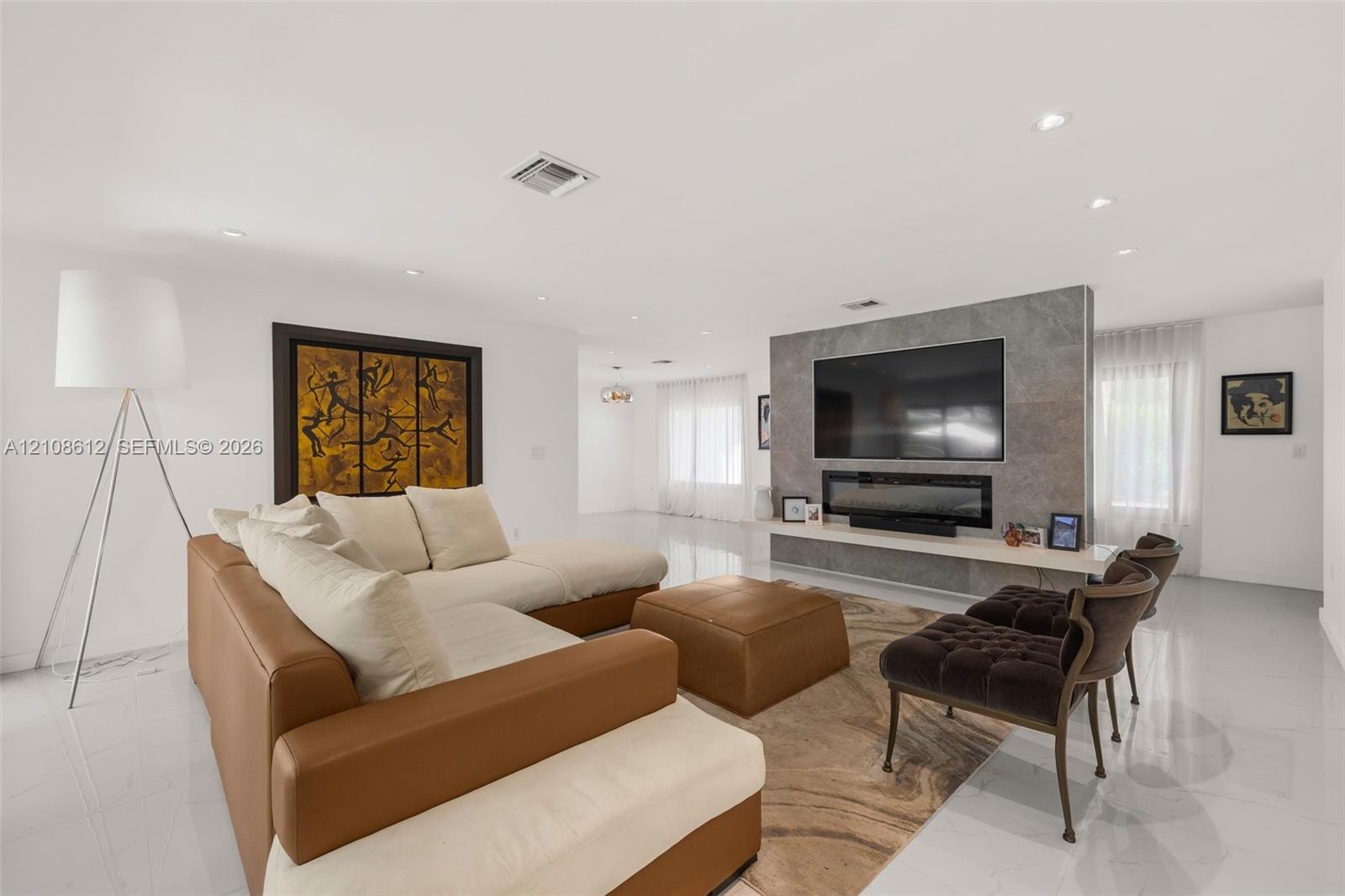 Open-concept room featuring high-gloss flooring, recessed lighting, and a floor-to-ceiling stone-tiled accent wall with a built-in linear fireplace an
