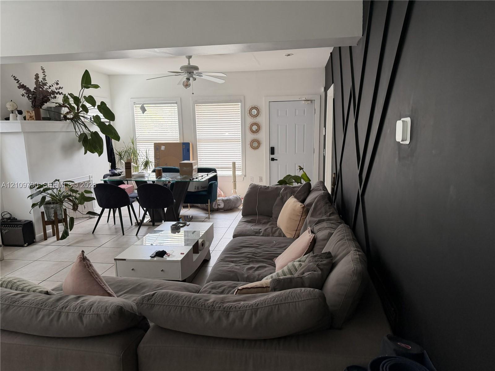 Accent wall featuring geometric molding, large-format tile flooring, ceiling fan, and fireplace surround