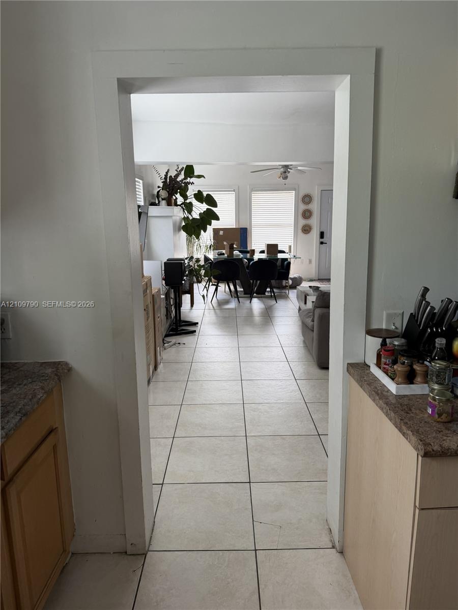 Wide entryway featuring ceramic tile flooring, light-toned wood cabinetry, and stone-finish countertops