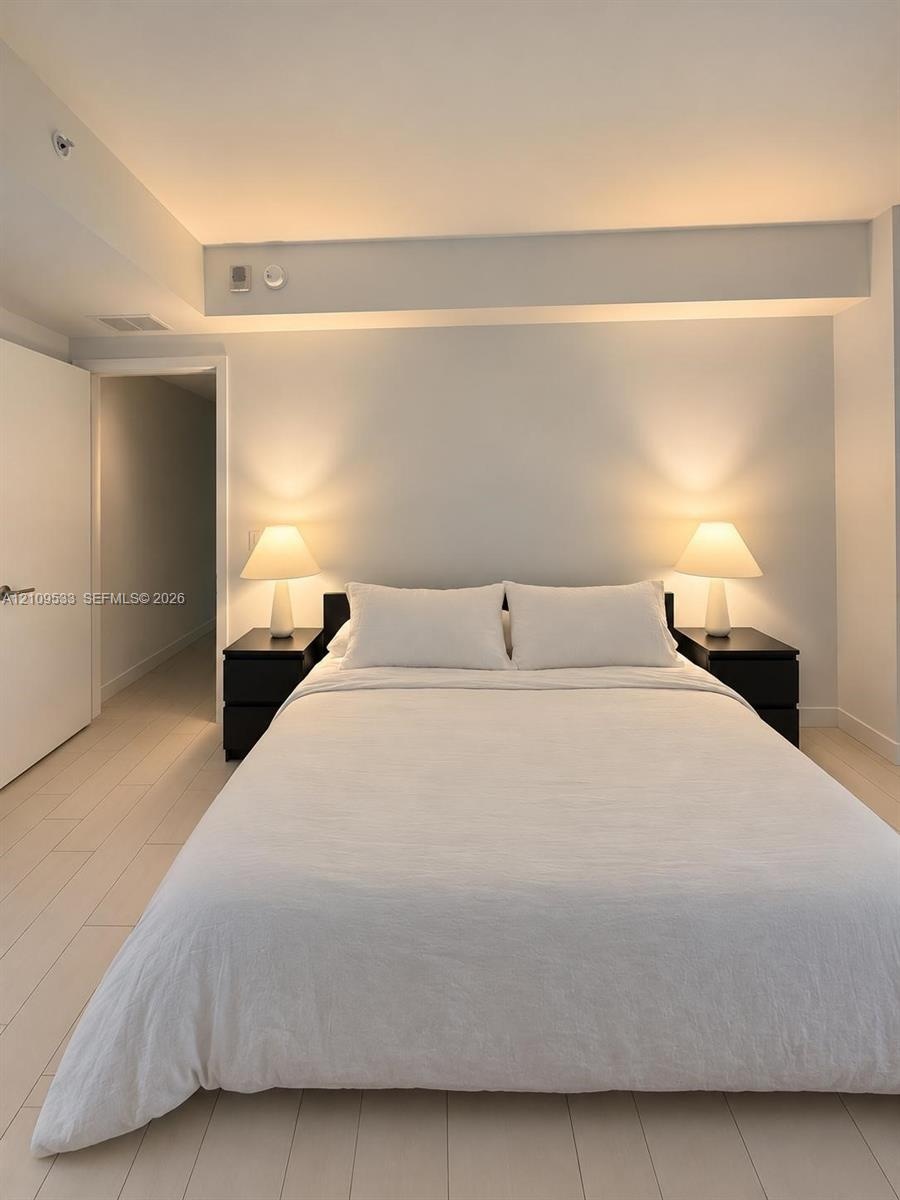 Neutral interior featuring light-toned wood-finish flooring, smooth ceilings, and minimalist recessed interior door