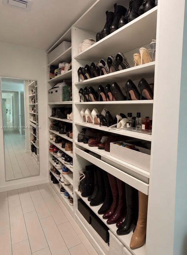 Custom floor-to-ceiling white shelving with multiple storage tiers and a full-length wall mirror