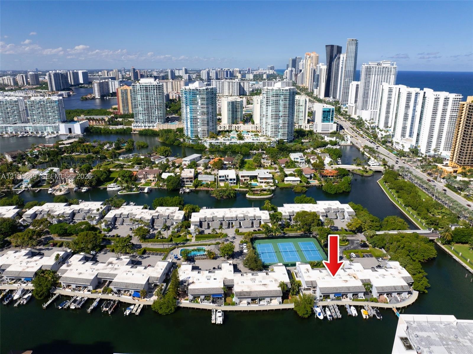 Aerial perspective featuring waterfront residential property with private boat slips, direct canal access, and communal tennis courts