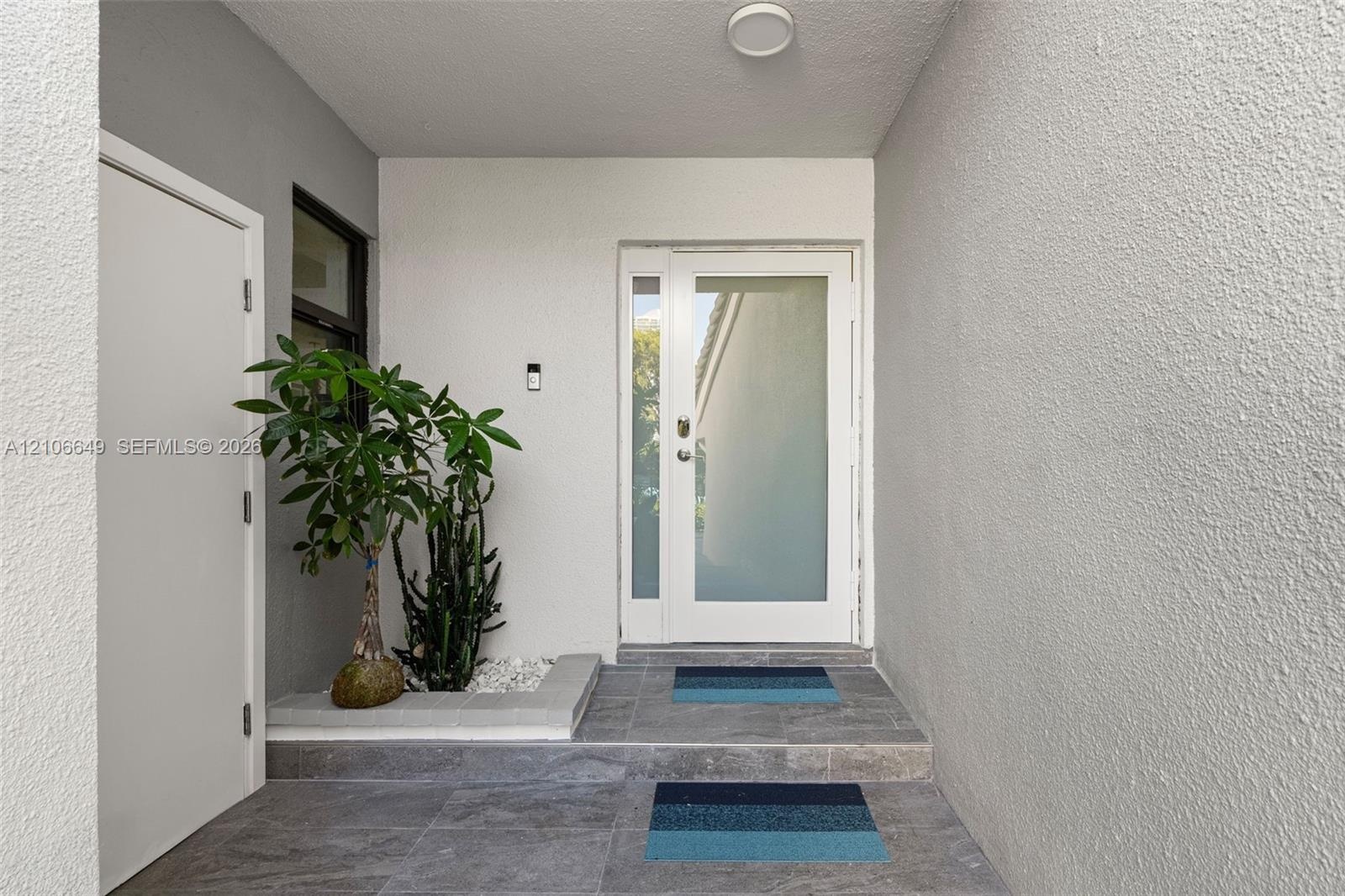 Entryway featuring a white door with a frosted glass panel, recessed ceiling lighting, textured wall finish, grey tiled flooring, and a built-in stone