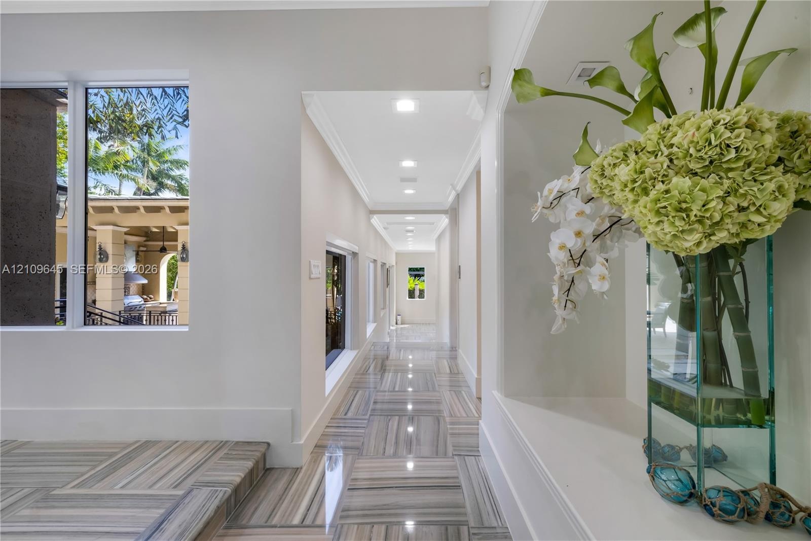 Hallway featuring polished stone flooring, recessed ceiling lighting, and a built-in recessed display niche