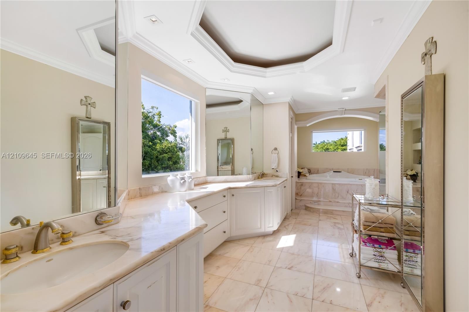 Bathroom featuring stone-finish flooring, white built-in cabinetry with stone countertops, an inset soaking tub with a stone surround, and an octagona