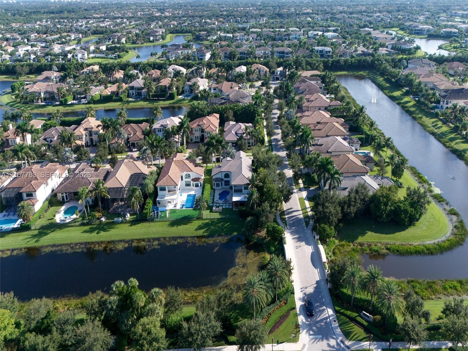 Aerial perspective of a residential neighborhood featuring waterfront lots, multi-story dwellings, tile roofing, and integrated canal systems