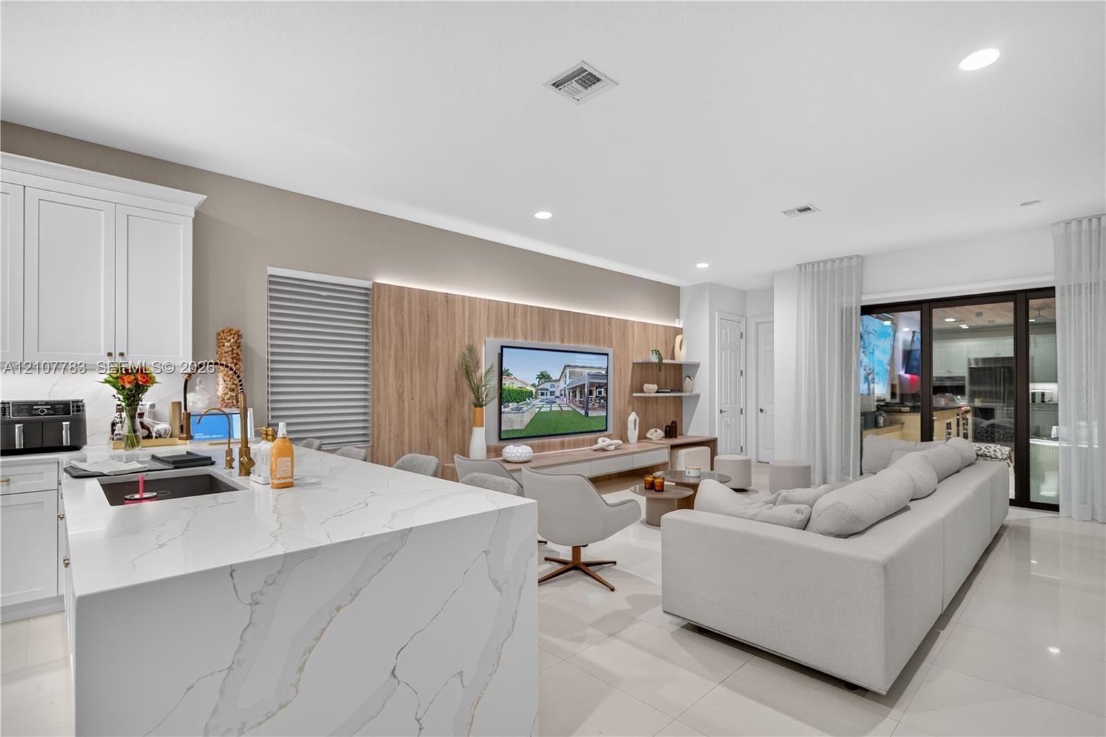 Kitchen featuring a waterfall-edge island with a stone-finish countertop, white cabinetry, integrated under-cabinet lighting, and large-format tile fl