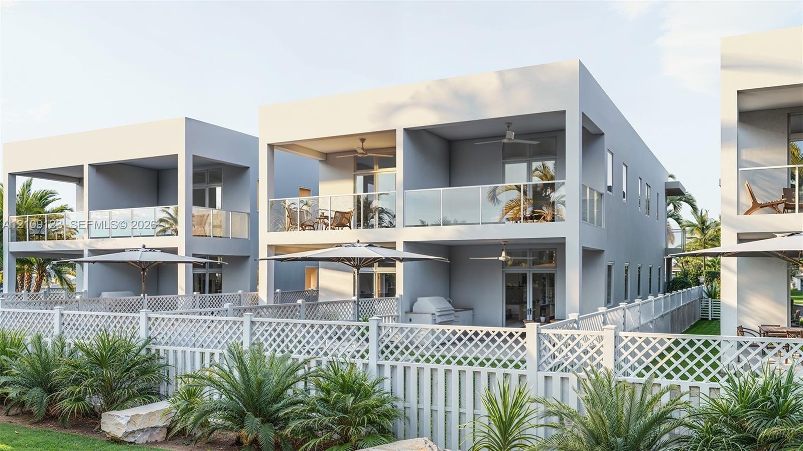 Contemporary multi-level structures featuring private covered balconies with glass railings, built-in outdoor kitchen components, and white lattice fe