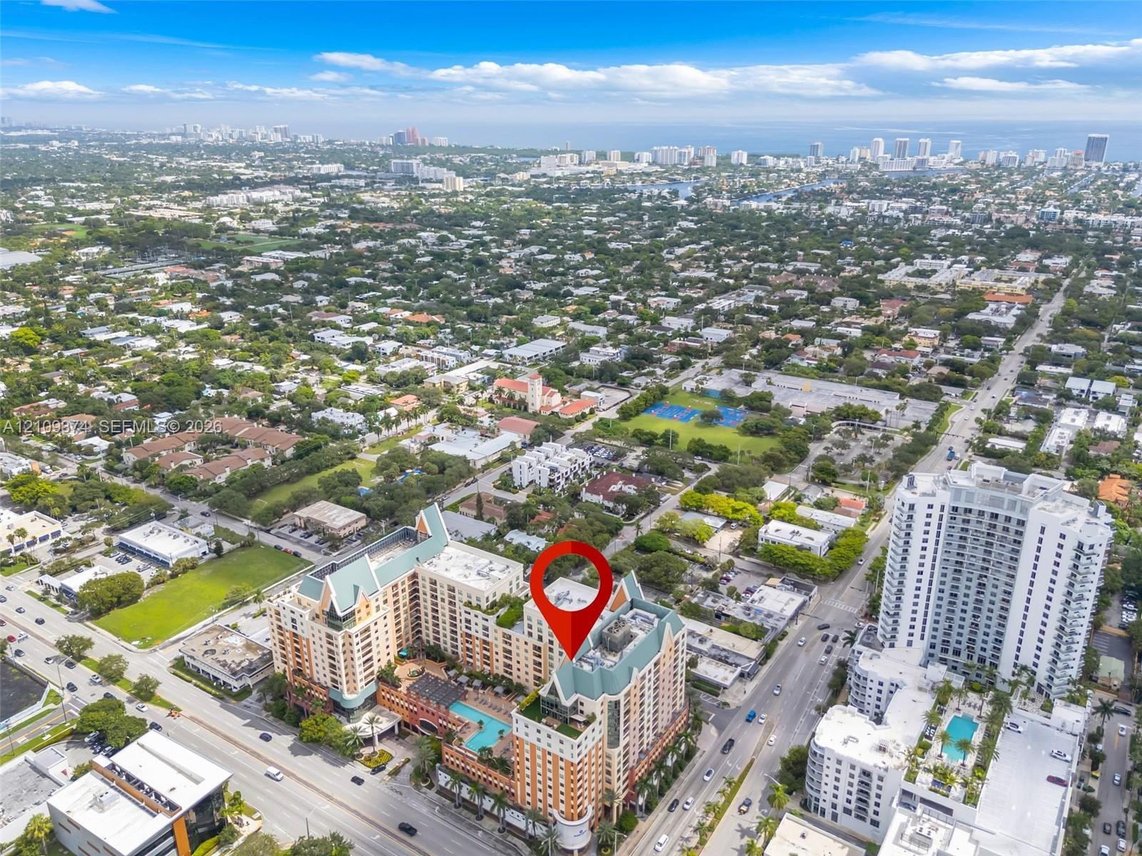 Aerial perspective of a multi-story residential building featuring a sprawling outdoor pool deck, terraced balconies, and a distinctive peaked rooflin