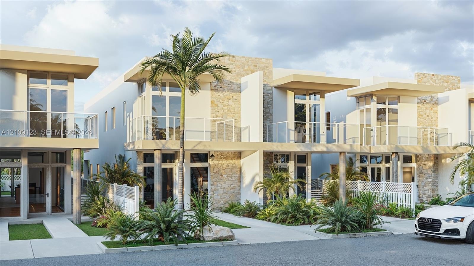 Contemporary multi-unit exterior featuring stacked stone accents, second-story glass-railed balconies, floor-to-ceiling windows, and concrete walkways
