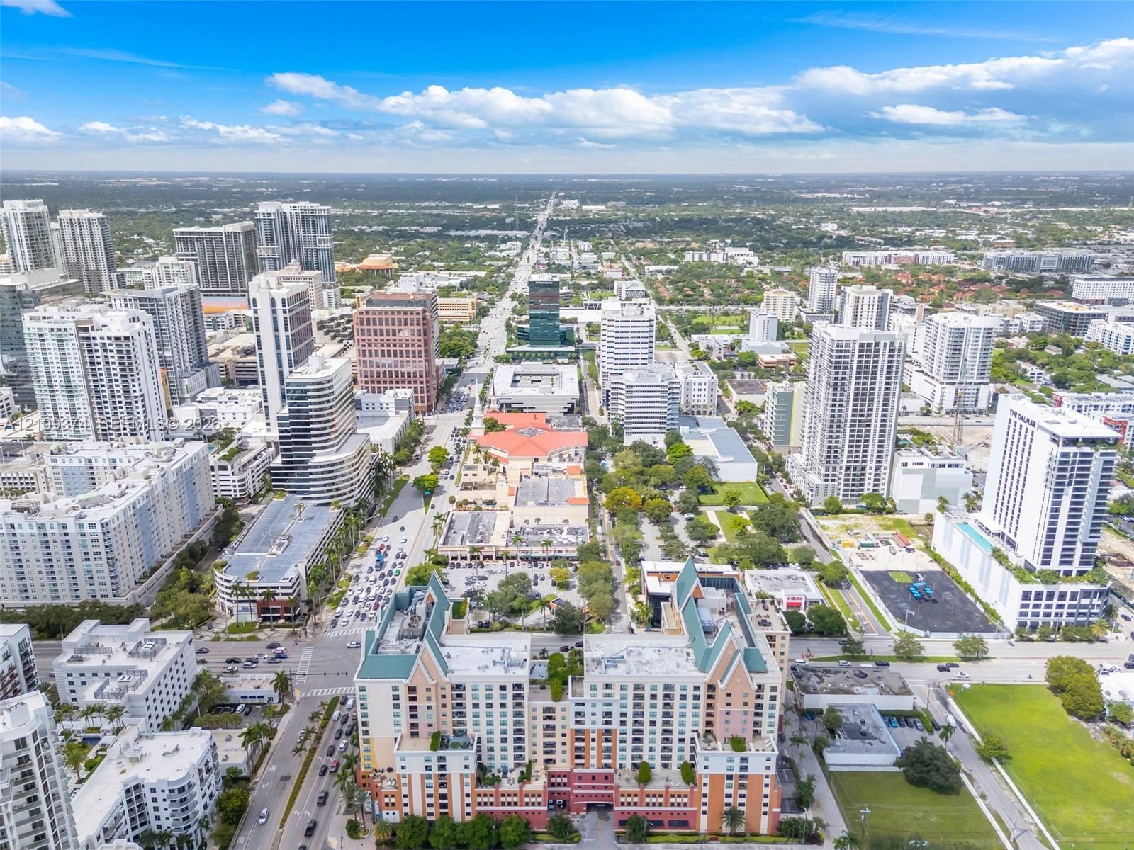Aerial perspective of a high-rise urban center featuring multi-story residential buildings, commercial structures, structured parking facilities, and 