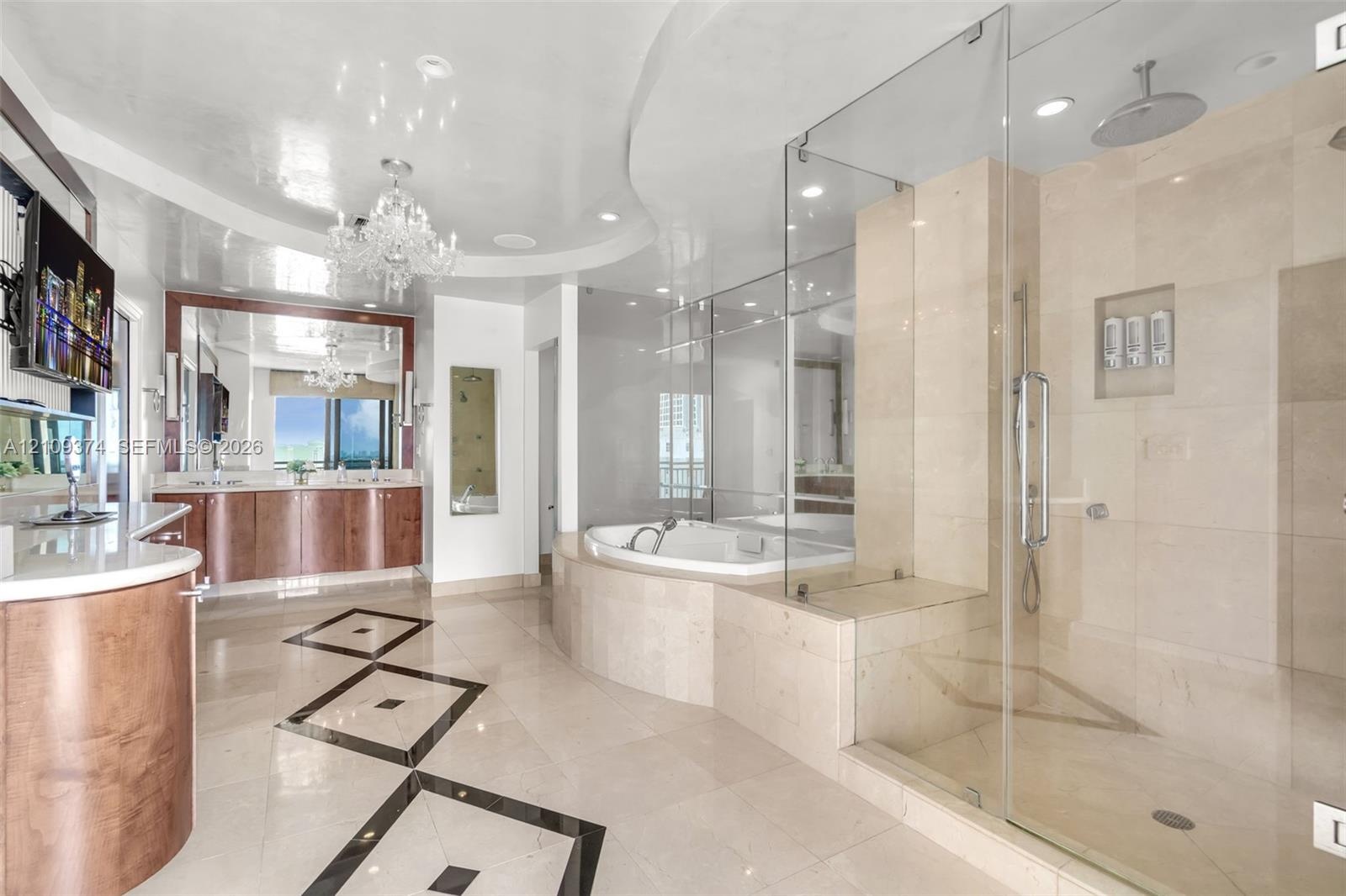 Bathroom featuring stone tile flooring with decorative inlay, a glass-enclosed shower with integrated shelving, a built-in soaking tub, wood-finish ca