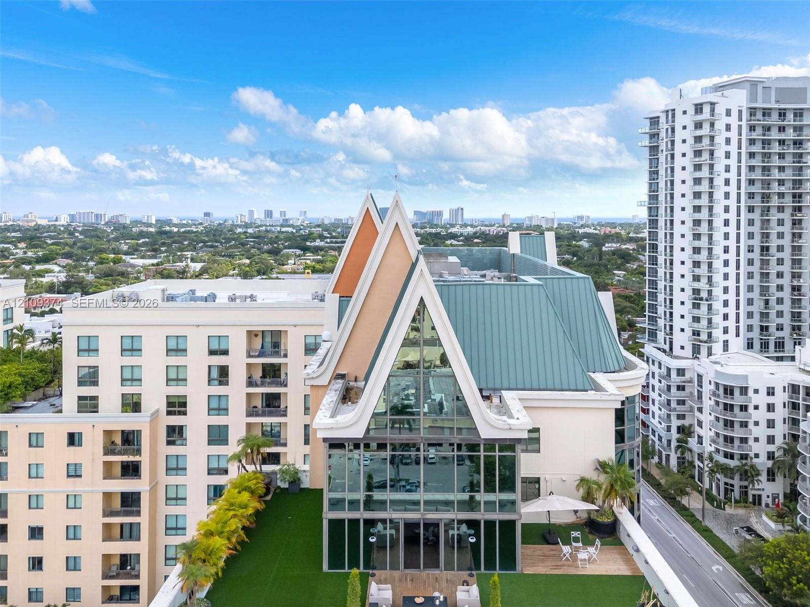 High-rise penthouse featuring an A-frame architectural design, expansive glass curtain wall, metal roofing, and a private rooftop terrace with artific