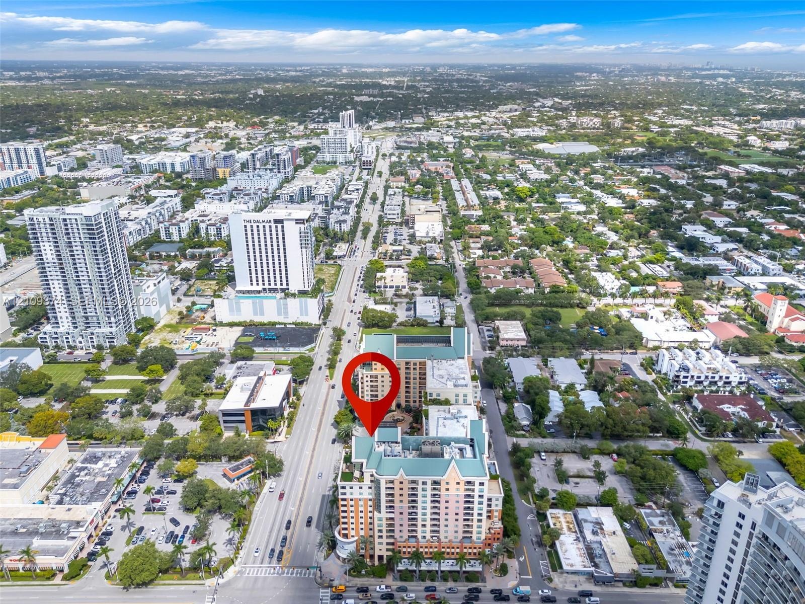 Aerial perspective of high-rise building featuring a multi-story exterior, ground-level parking, and prominent location within an established metropol