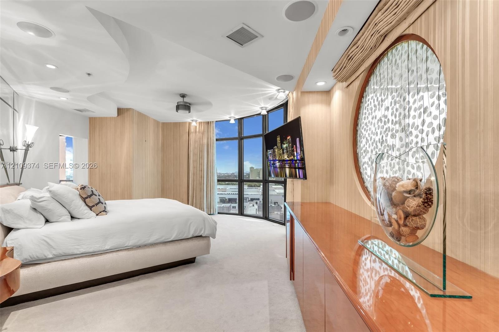 Floor-to-ceiling windows with panoramic exterior exposure, curved architectural ceiling detail, built-in cabinetry with high-gloss finish, circular wa