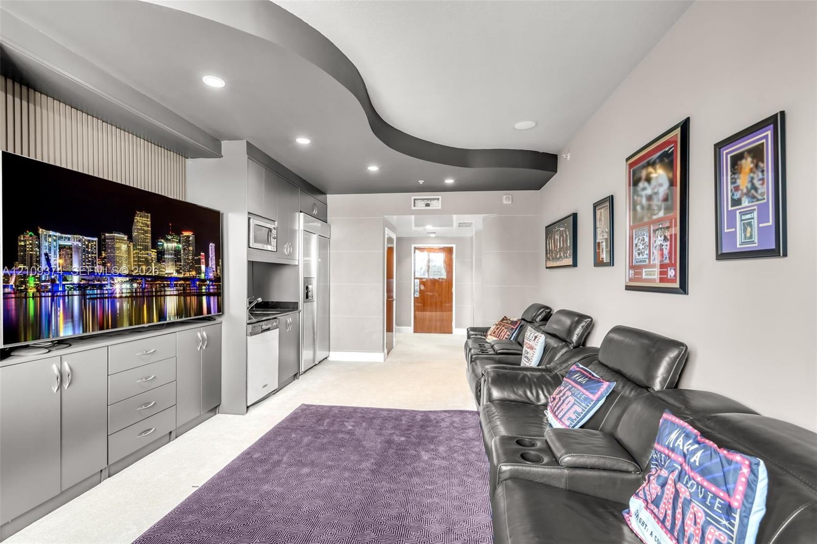 Custom built-in cabinetry with integrated microwave, stainless steel refrigerator, dishwasher, recessed ceiling lighting, and a distinctive curved arc